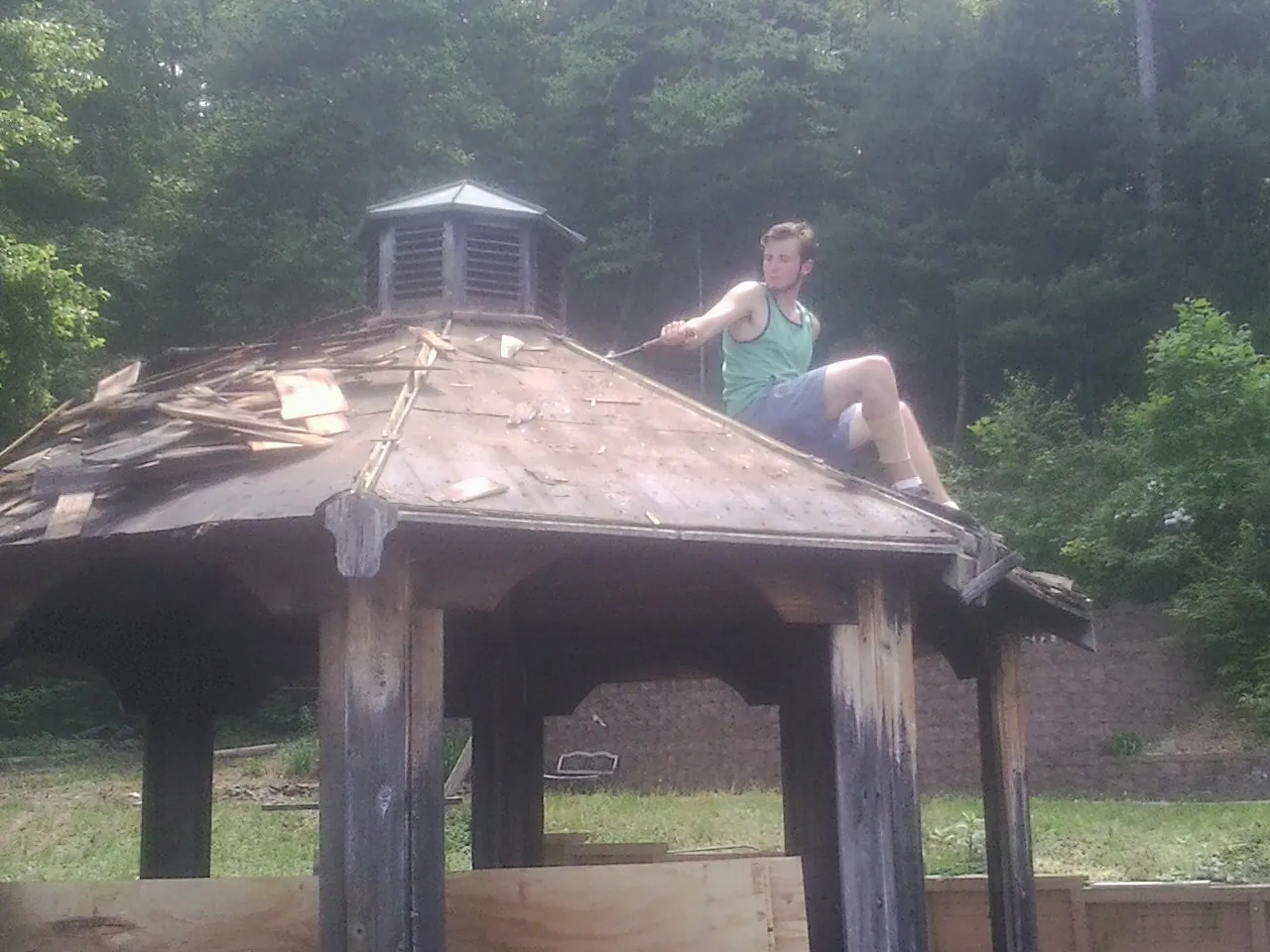 Tearing the old roof off a wooden gazebo before new shakes in Walnut Grove