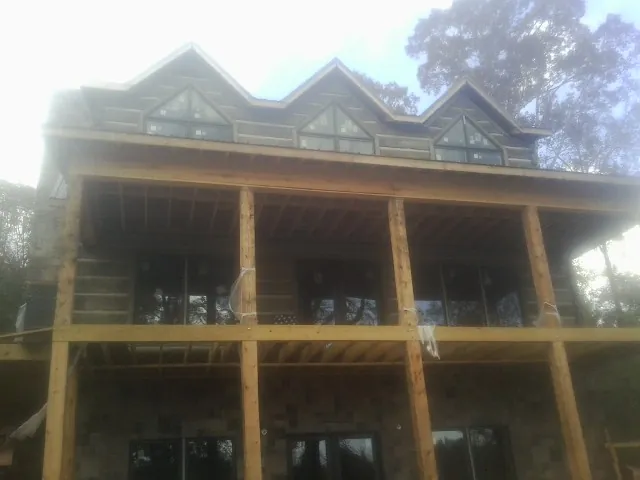 Dormers and porch framing on a large log home under construction — Roof Coating work by our crew in Walnut Grove