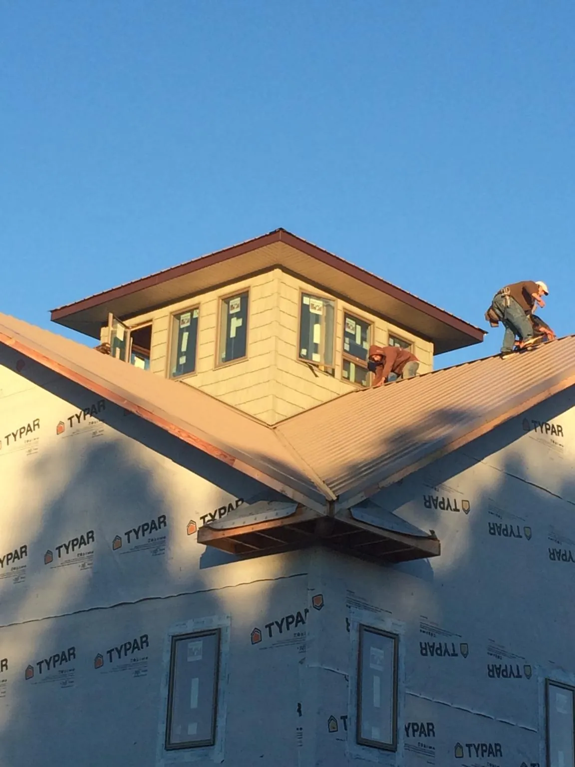 Roofers working around a rooftop cupola on a new metal roof at sunset — Roof Waterproofing in Walnut Grove by Roofing Brothers